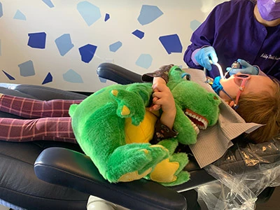 pediatric patient holding stuffed animal in dentist chair
